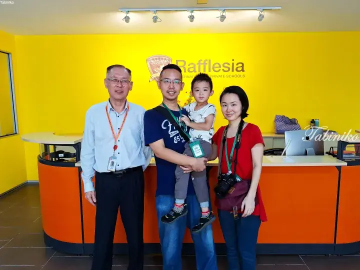 Family posing with a school representative at Rafflesia International & Private Schools reception desk.