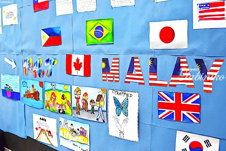 Classroom bulletin board displaying hand-drawn flags of Malaysia, Canada, Japan, and others alongside student artwork.