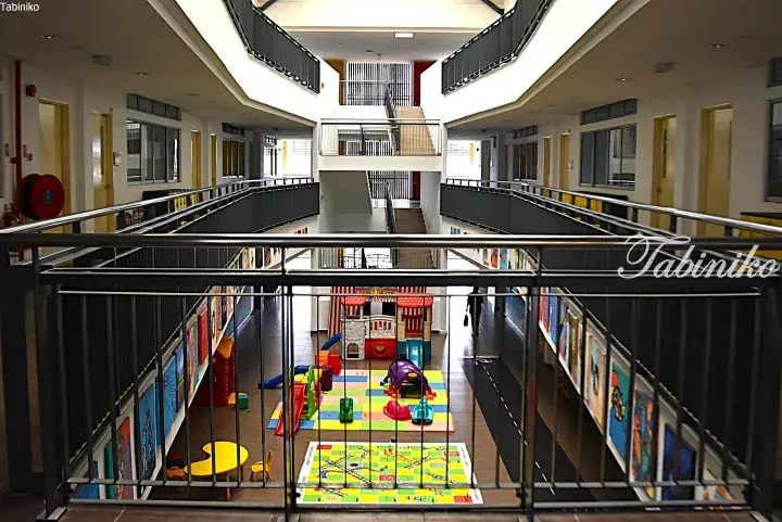 Modern multi-level school atrium with colorful play area and artwork on the ground floor.