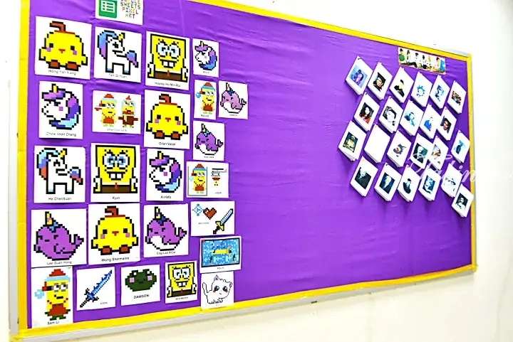 Purple bulletin board displaying pixel art creations by students alongside a collection of polaroid photos.