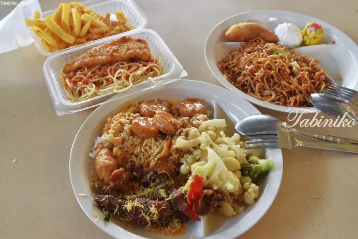 Variety of Malaysian hawker food including fried rice, noodles, and chicken on a table.