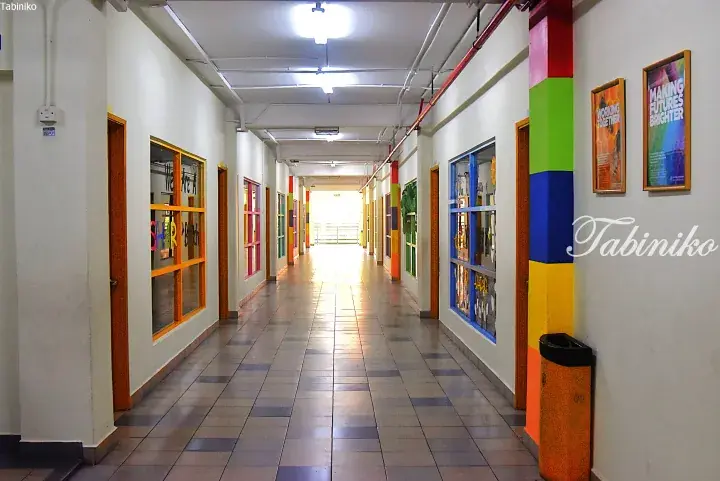 Colorful hallway with bright pillars and posters in a Malaysian school or community center.