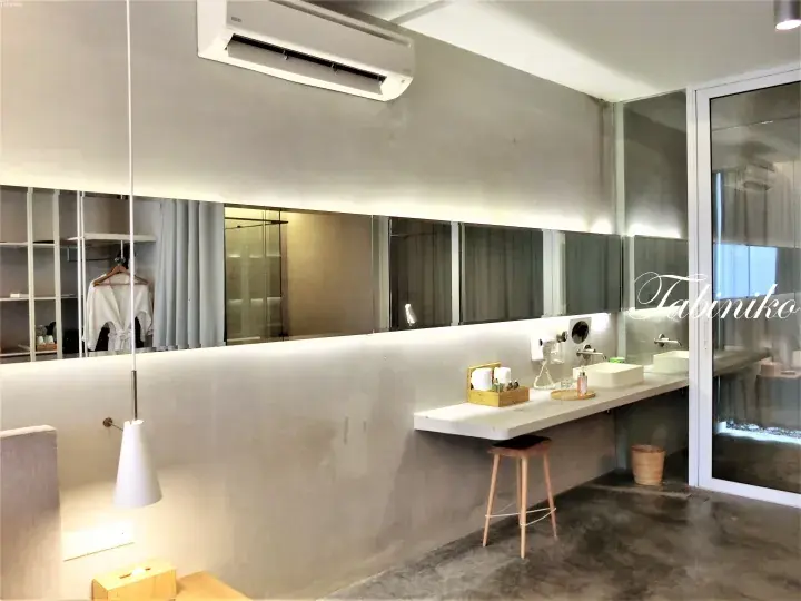 Modern minimalist bathroom with concrete walls, long mirror, and floating vanity in a Malaysia property.