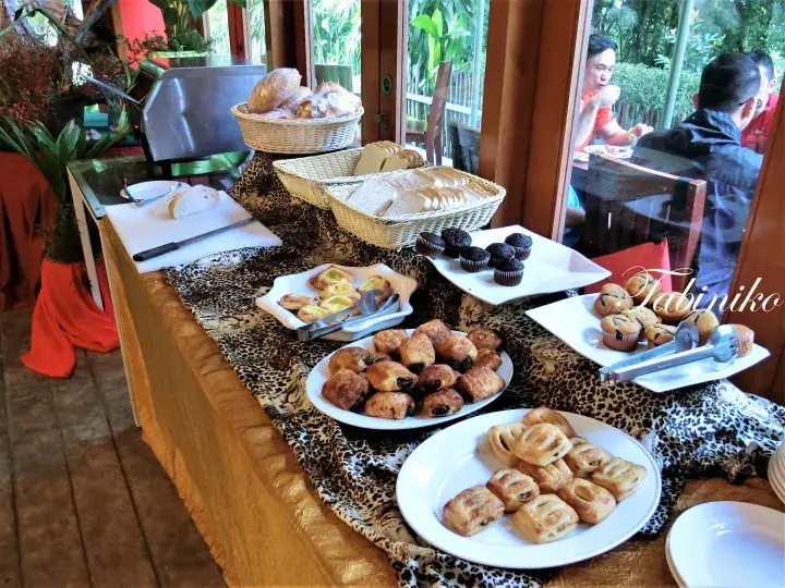 Buffet table with leopard print runner displaying bread, pastries, and muffins at a Malaysian resort.
