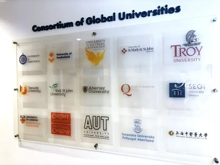 Wall display of the Consortium of Global Universities featuring logos of partner institutions like University of Greenwich and AUT.