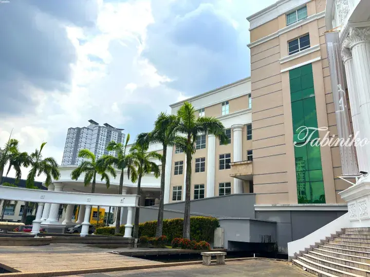 SEGi College Subang Jaya campus featuring beige buildings with white columns, palm trees, and a modern residential tower in the background.