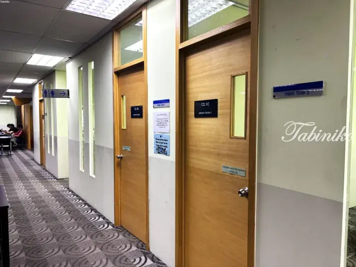Wooden study rooms labeled Think Tank 2 and Library Room C in a quiet library corridor with patterned carpet.