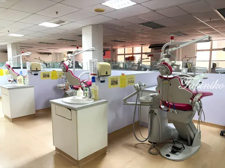 Modern dental clinic interior with pink and white dental chairs, sinks, and equipment in a bright, clean room.