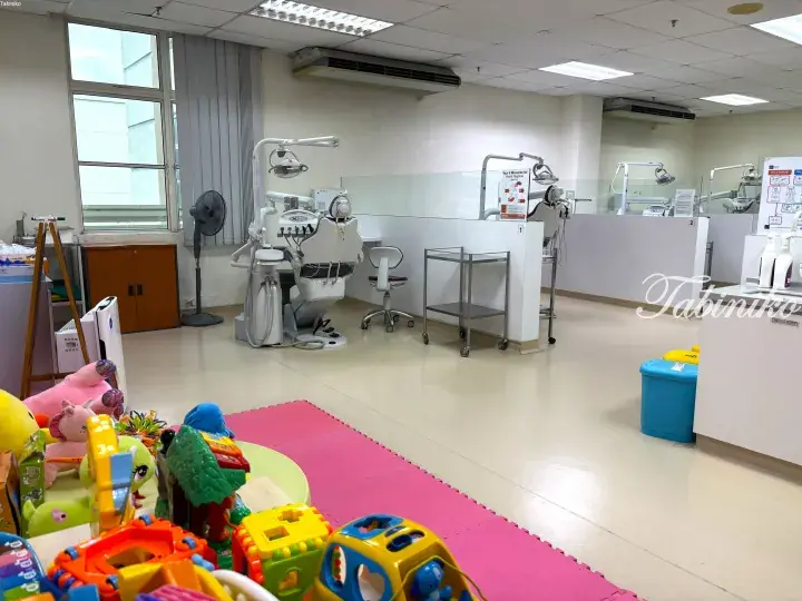 Child-friendly dental clinic interior with colorful toys on a play mat and modern dental chairs in the background.