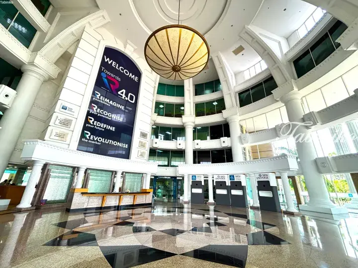 Grand atrium of SEGi University & Colleges featuring white columns, a large circular chandelier, and a digital display welcoming visitors to iR4.0.