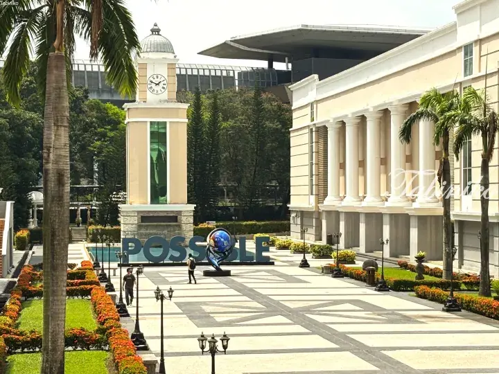 Clock tower and POSSIBLE sign at Sunway University campus with palm trees and classical architecture.