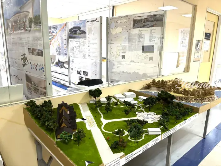 Architectural models and design boards for McLaren Park and Volvo showroom displayed in a studio.