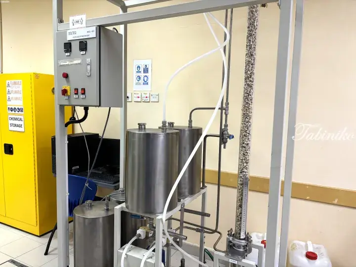 Industrial liquid-liquid extraction unit with stainless steel tanks and control panel in a laboratory setting.