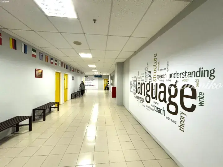 Bright university hallway with flags, benches, and a large ’language’ word art wall.