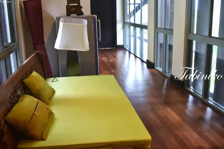 Bright bedroom with wooden floor, yellow mattress, and large glass windows in a Malaysian property.
