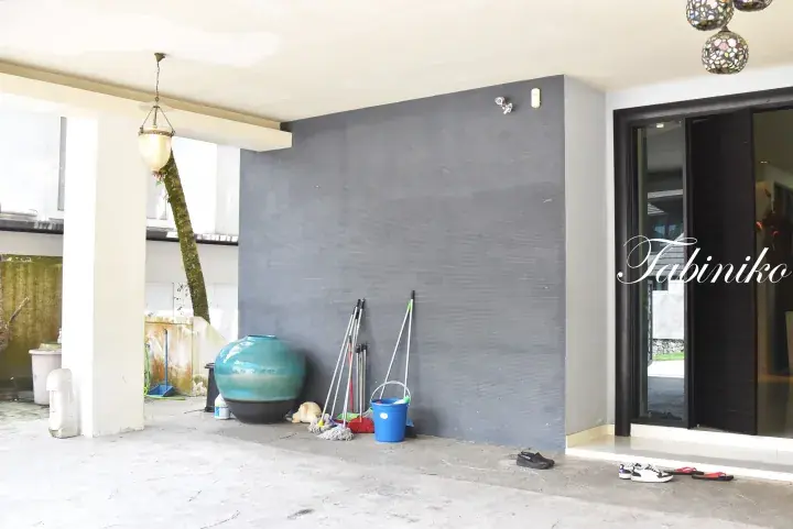 Covered outdoor area with grey textured wall, large blue ceramic jar, cleaning supplies, and shoes near entrance.
