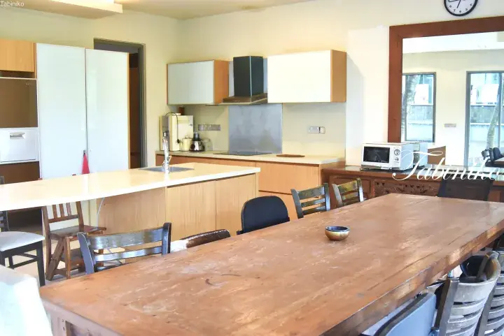 Spacious kitchen with wooden island and large dining table in a modern Malaysian home.
