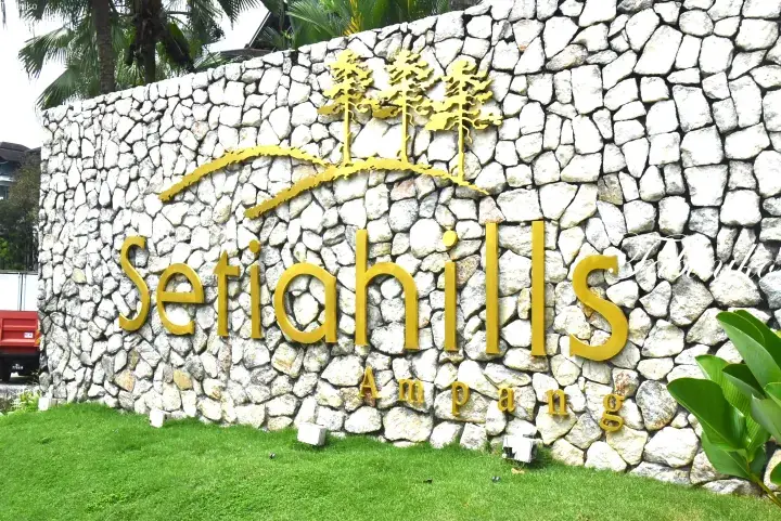 Golden Setia Hills Ampang sign mounted on a white stone wall with trees and greenery in the background.