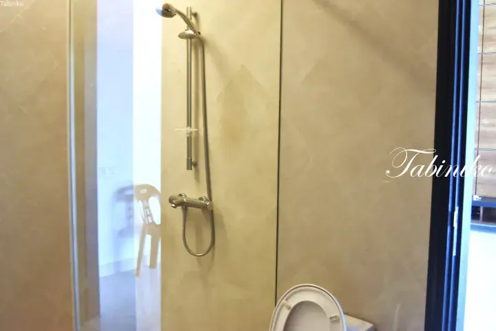 Modern bathroom with beige tiled walls, a chrome shower fixture, and a glass partition.