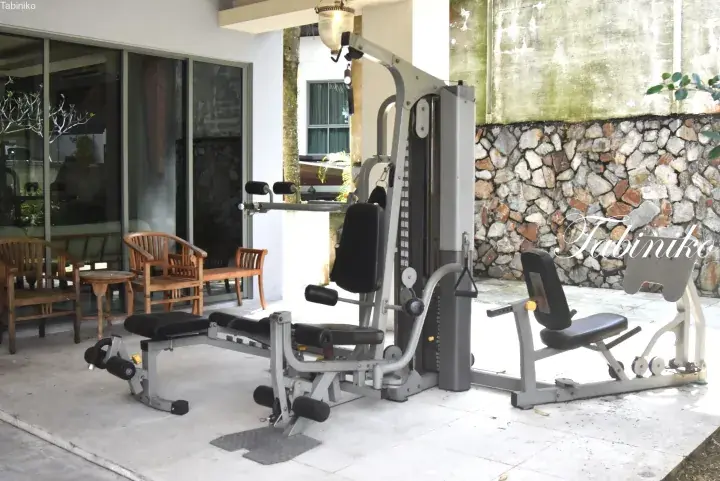 Outdoor gym area with weight machines and wooden chairs on a patio at a Malaysia property.
