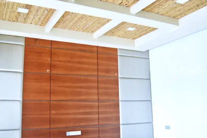 Interior view of a modern room featuring a bamboo ceiling and a wall with alternating brown wood and grey panels.