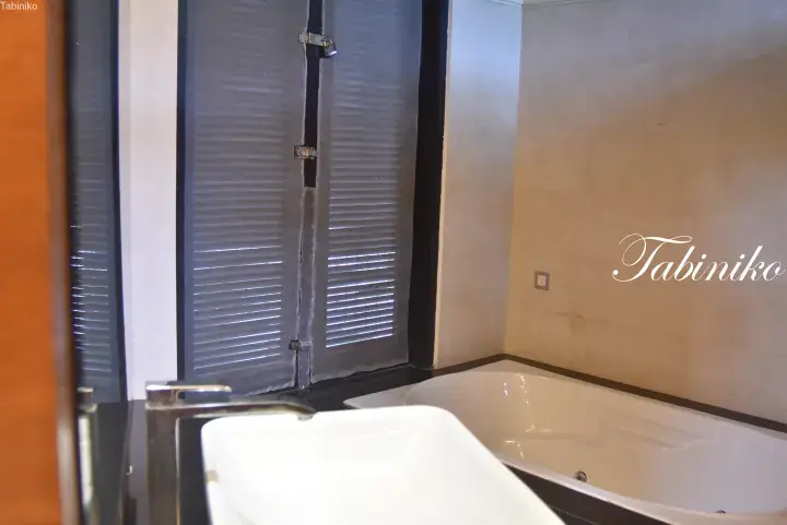 Modern bathroom featuring a white bathtub, rectangular sink, and dark-framed window with louvers.