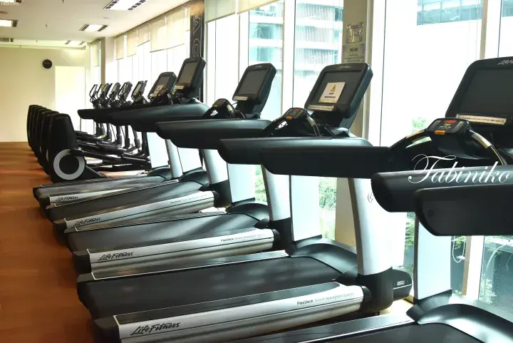 Row of Life Fitness treadmills with FlexDeck shock absorption in a bright gym with large windows overlooking city buildings.