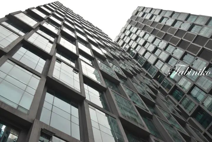 Low-angle view of modern residential towers with distinctive geometric concrete facades and large glass windows.