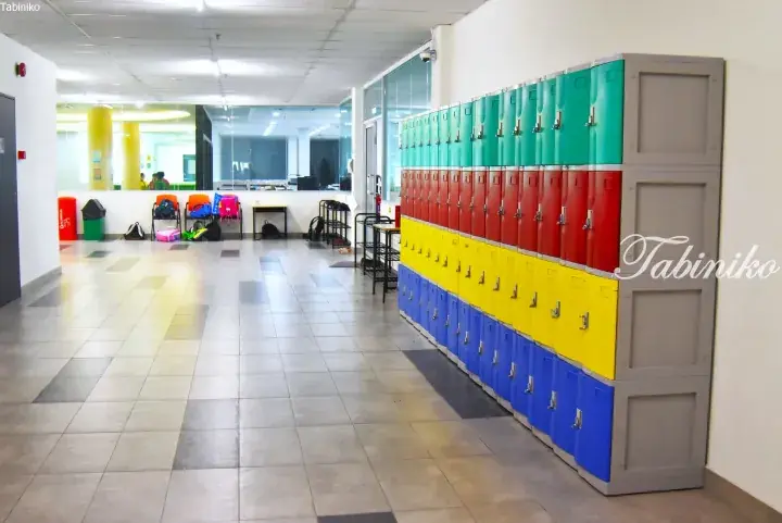 Colorful lockers in a modern school hallway with students and bags in the background