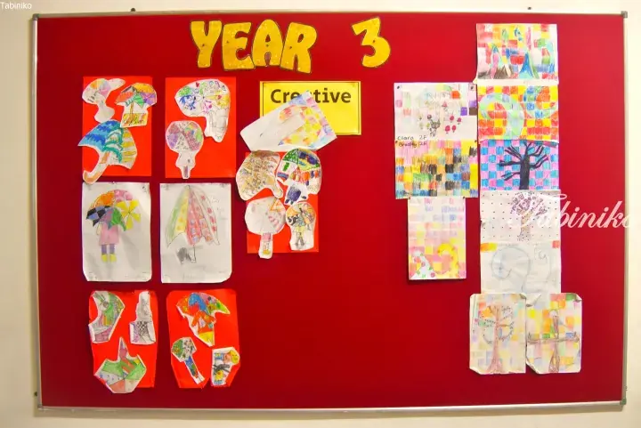 Year 3 creative art display board featuring colorful children’s drawings of umbrellas and trees on red background.
