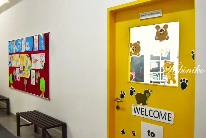 Yellow classroom door with bear decorations and a welcome sign in a Malaysian school hallway.