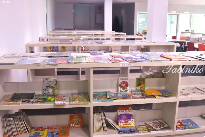Rows of low white bookshelves filled with children’s books in the Junior Section of a modern library.