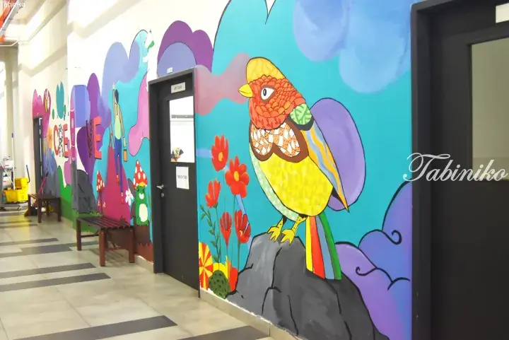Colorful mural of a bird and flowers in a hallway with an Art Studio door.