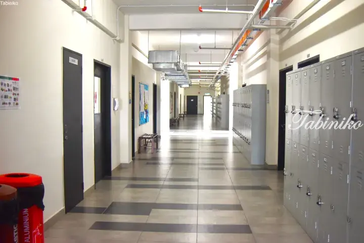 Modern school corridor with grey lockers, tiled floors, and exposed ceiling ducts in a Malaysian educational facility.