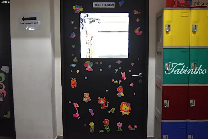 Black classroom door labeled Year 3 Newton with colorful animal stickers and a view of lockers nearby.