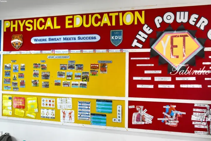 School bulletin board displaying Physical Education achievements, fitness charts, and motivational quotes.