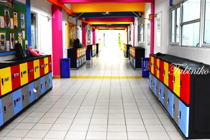 Colorful school hallway with vibrant lockers and bright pink pillars in a Malaysian educational facility.