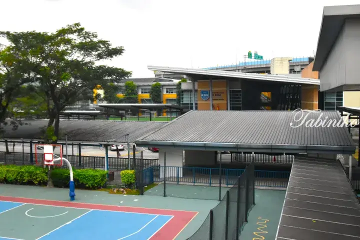 Sri KDU International School campus featuring a colorful basketball court, covered walkways, and modern buildings.