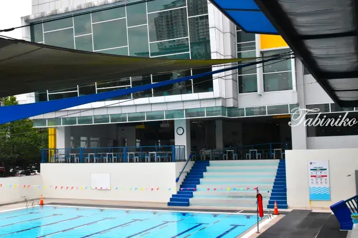 Modern swimming pool with blue lane dividers and tiered seating at a Malaysian facility.