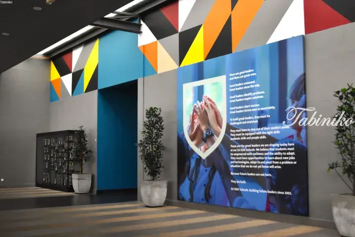 Interior hallway of Sri KDU Schools featuring a large motivational poster about leadership and a trophy display cabinet.