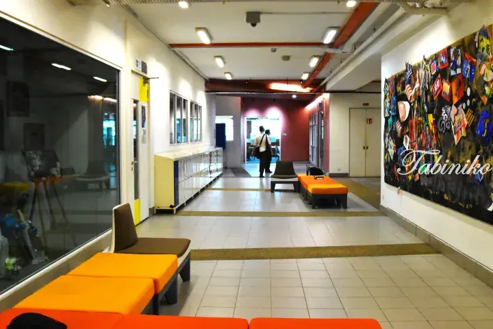 Modern hallway with orange lounge seating and a colorful art display wall in a Malaysian property.