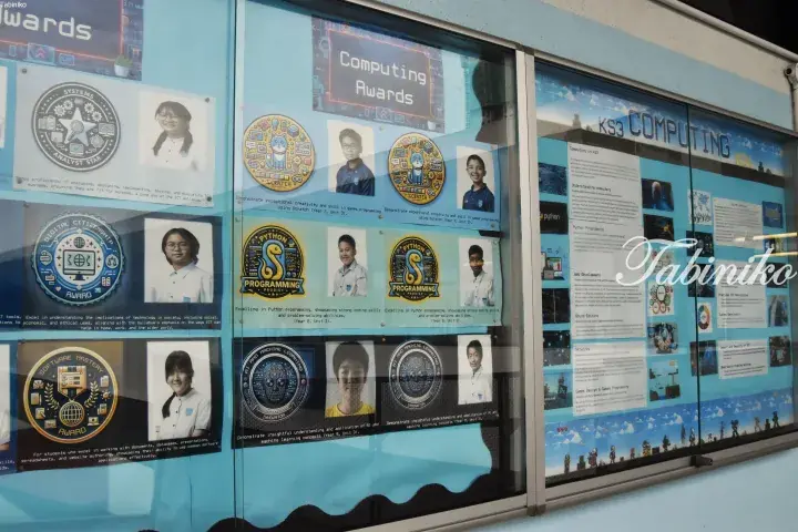School bulletin board displaying student Computing Awards with photos and badges for Scratch, Python, and AI skills.