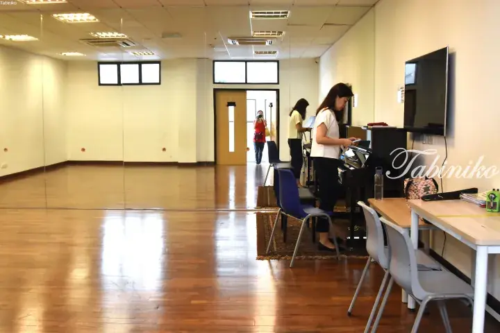 Woman practicing piano in a spacious music studio with wooden floors and wall mirrors.