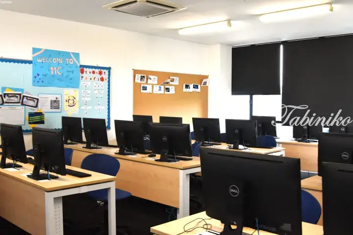 Rows of Dell computers in a modern classroom with bulletin boards and blue chairs.