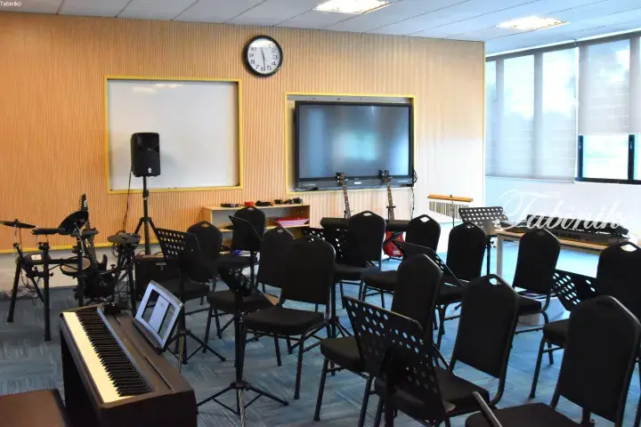 Music classroom with chairs, keyboards, guitars, and a whiteboard for lessons.
