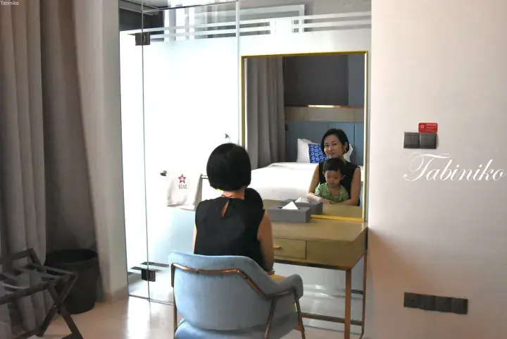 Woman and child reflected in a mirror at a vanity desk in a Star Suites hotel room.