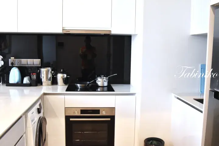 Modern kitchen with white cabinetry, Bosch oven, Samsung washing machine, and induction cooktop in a Malaysian property.