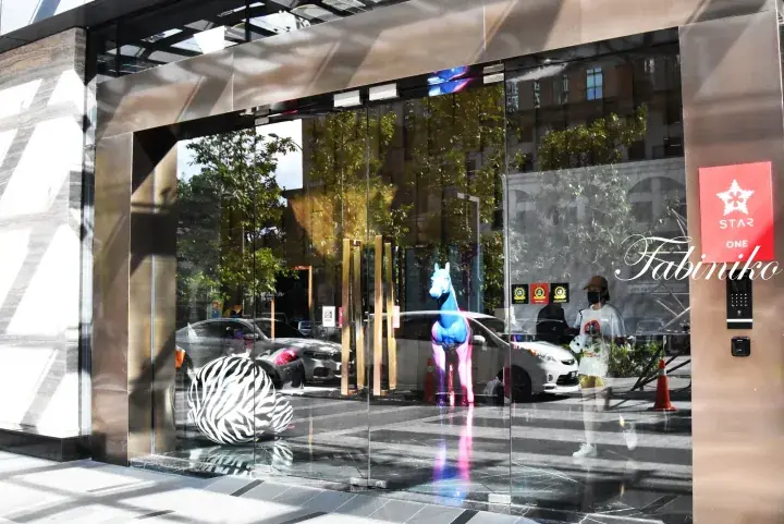 Glass entrance to Star One building featuring a blue horse statue and zebra print decor.