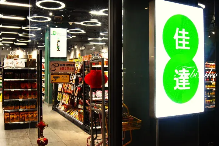 Entrance of a Jia Da supermarket in Malaysia, featuring a bright green logo sign and shelves stocked with various grocery items.