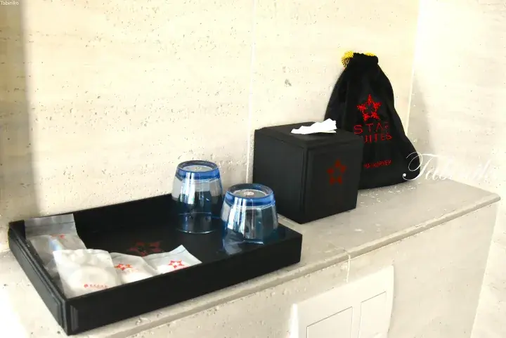 Black tray with glasses and toiletries, tissue box, and hair dryer bag at Star Suites hotel.